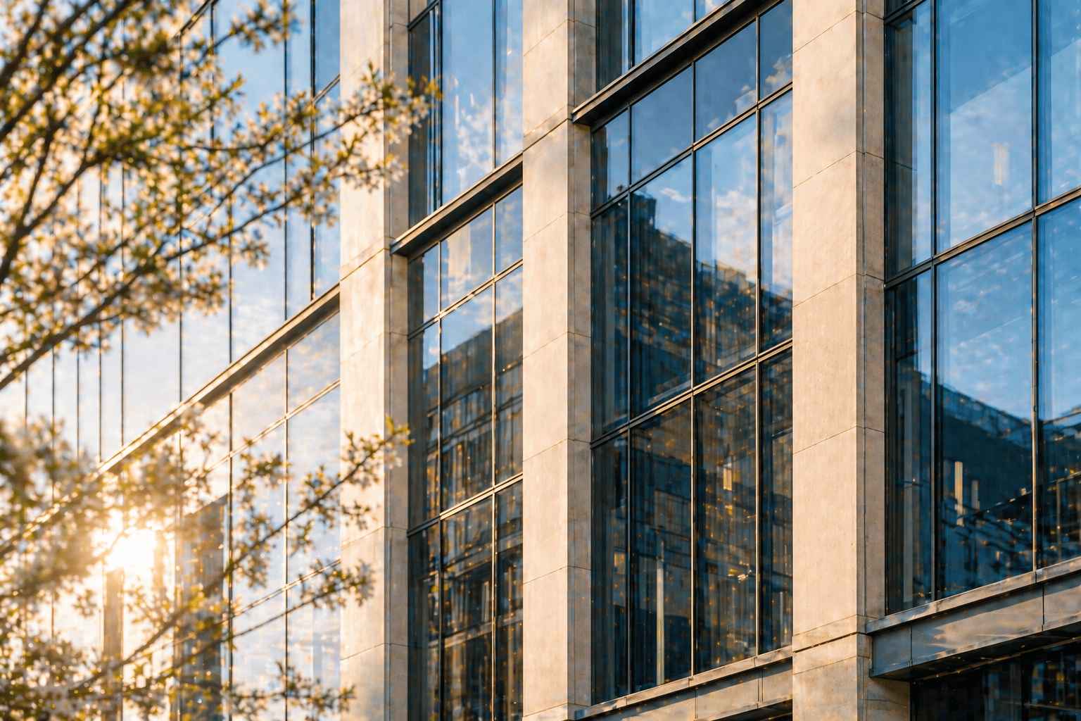 Office building with reflective glass windows and sunlight, showcasing contemporary architecture.